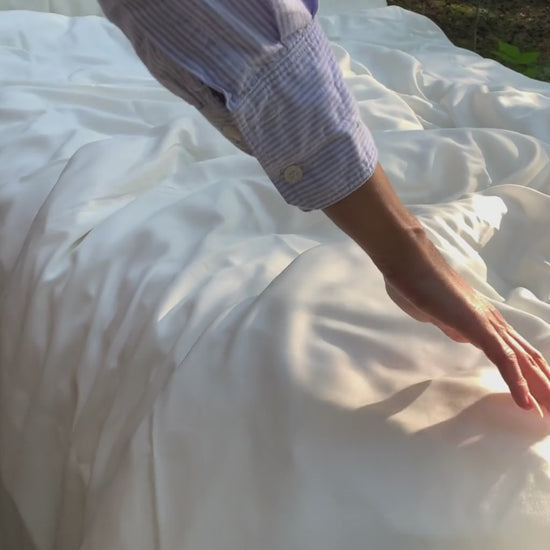 Lyocell Bettwäsche mit Eukalyptus Zellstoff aus 100% Tencel in Weiß, Hand streicht über das Bett